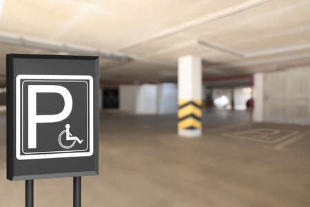 Sign with wheelchair symbol in car parking garage, space for textの写真素材