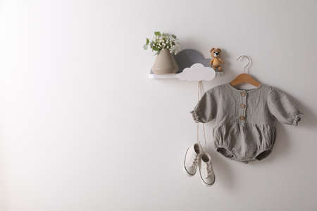 Cute baby clothes and shoes hanging on white wall. Space for textの写真素材