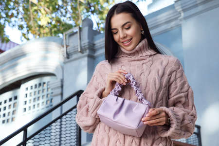 Fashionable young woman with stylish bag on city street. Space for textの写真素材
