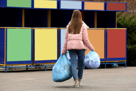Woman with garbage at recycling point outdoors, back viewの写真素材