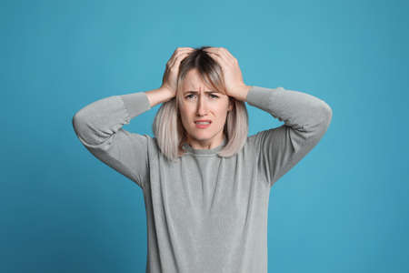 Woman suffering from headache on light blue background