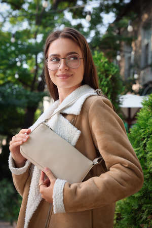 Fashionable young woman with stylish bag on city streetの写真素材