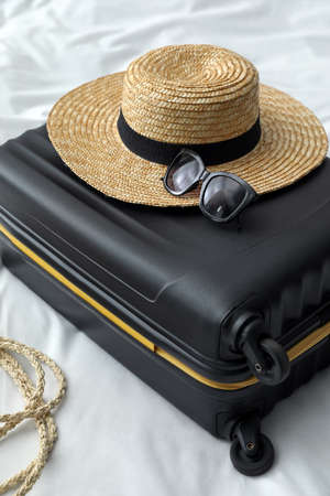 Suitcase packed for trip and summer accessories on bedの写真素材