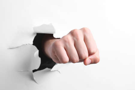 Man breaking through white paper with fist, closeupの写真素材
