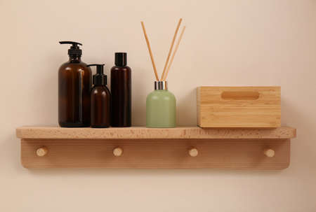 Wooden shelf with soap dispensers and aromatic reed freshener on beige wall. Interior elementの写真素材