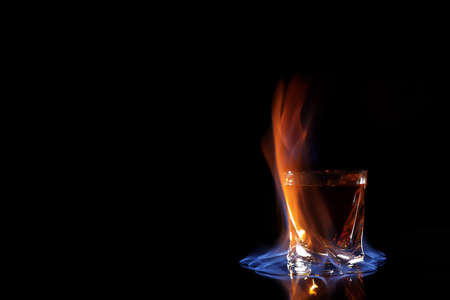 Glass with flaming vodka on black background, space for textの写真素材
