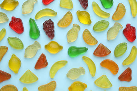 Tasty jelly candies in shape of different fruits on light blue background, flat layの写真素材