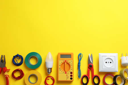 Flat lay composition with electrician's tools and accessories on yellow background, space for textの写真素材