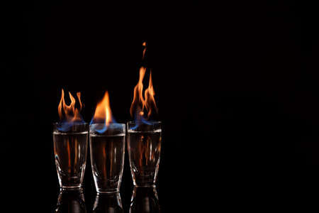 Flaming vodka in shot glasses on black background, space for textの写真素材