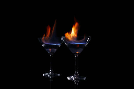 Cocktail glasses with flaming vodka on black backgroundの写真素材