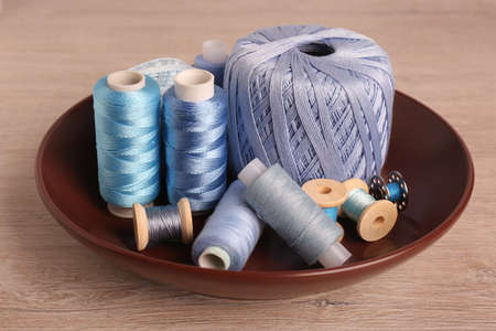 Color sewing threads in bowl on wooden table