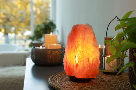 Himalayan salt lamp, houseplant and candles on table indoors, space for textの写真素材