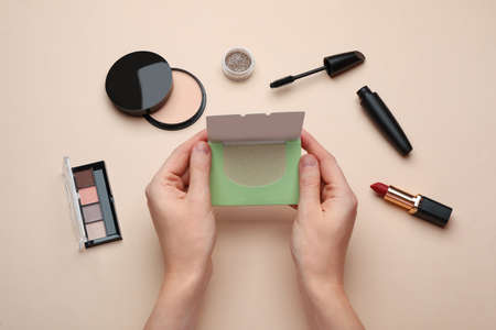 Woman with package of oil blotting tissues and decorative cosmetics on beige background, top view. Mattifying wipesの写真素材
