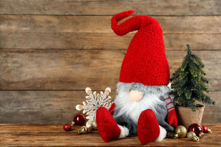 Cute Christmas gnome and festive decor on table against wooden background. Space for textの写真素材