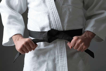 Karate coach wearing kimono and black belt on gray background, closeupの写真素材