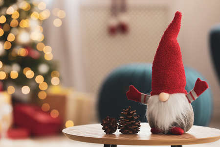 Cute Christmas gnome on wooden table in room, space for textの写真素材