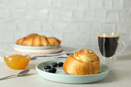 Delicious bun with blueberries, jam and coffee on white tableの写真素材