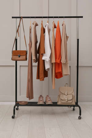 Rack with stylish women's clothes, shoes and accessories near light wall in roomの写真素材
