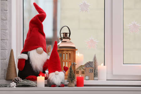 Cute Christmas gnomes and other festive decorations on windowsill in room, space for textの写真素材