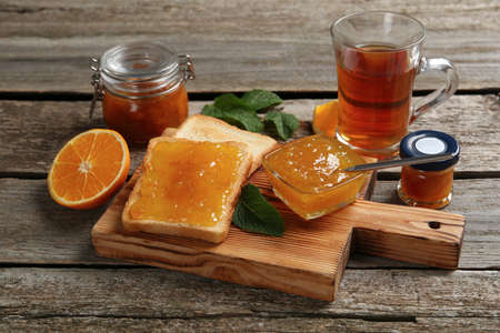 Delicious toasts served with jam and tea on wooden tableの写真素材
