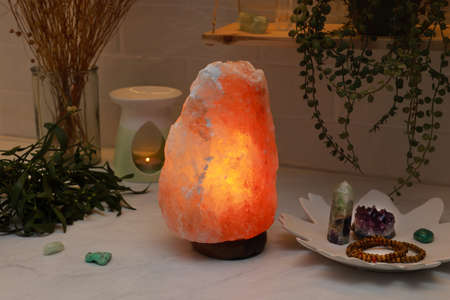 Himalayan salt lamp, crystals and oil diffuser on white table near brick wallの写真素材