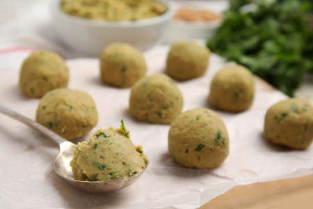 Raw falafel balls and spoon on parchment, closeupの写真素材
