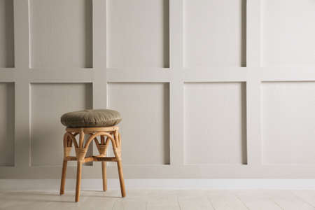 Stylish wooden stool with cushion near white wall, space for text. Interior elementの写真素材
