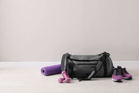 Gray bag and sports accessories on floor near light wall, space for textの写真素材