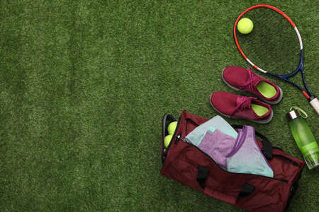 Gym bag and sports equipment on green grass, flat lay. Space for textの写真素材