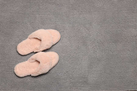 Slippers on soft gray bath mat, flat lay. Space for textの写真素材