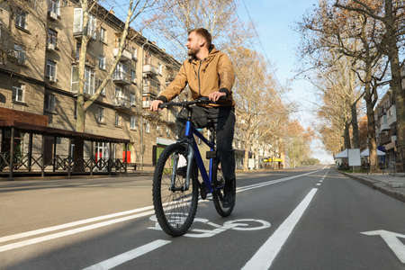 Handsome man riding bicycle on lane in cityの写真素材