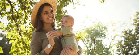 Happy mother with cute baby in park on sunny day, space for text. Banner design