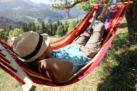 Man resting in hammock outdoors on sunny dayの写真素材