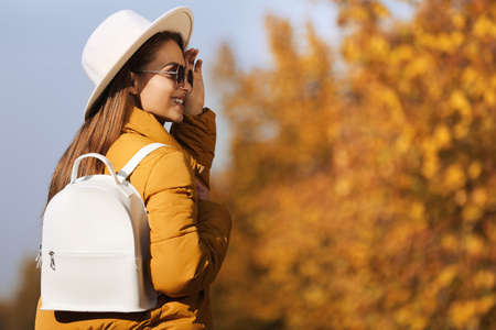 Young woman with stylish backpack on autumn day, space for text