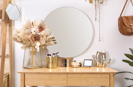 Modern wooden dressing table with decorative elements and makeup products in roomの写真素材