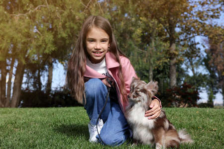 Little girl with her cute dog in park. Autumn walkの写真素材