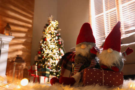Cute Christmas gnomes and gift in room with festive decorations. Space for textの写真素材