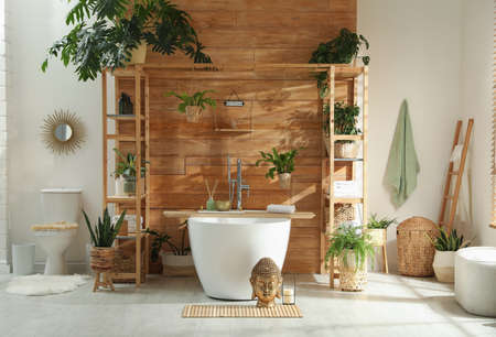 Stylish bathroom interior with white tub and green houseplants near wooden wall. Idea for designの写真素材