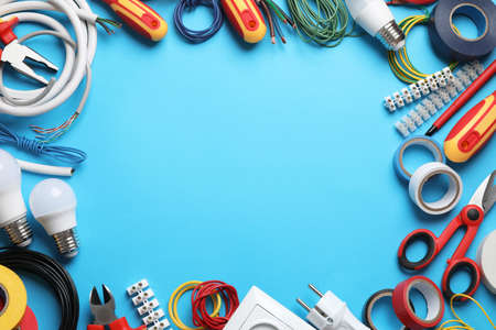 Frame of electrician's tools and accessories on light blue background, flat lay. Space for textの写真素材