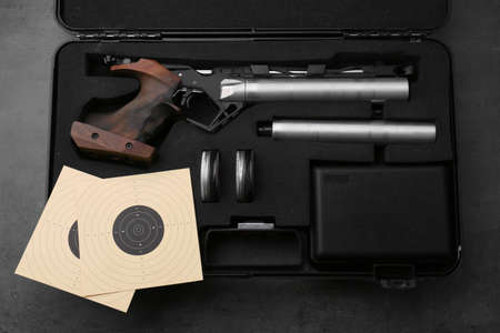 Case with sport pistol and accessories on black table, top view. Professional gunの写真素材