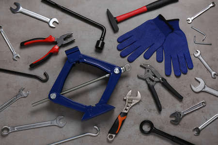 Car scissor jack, gloves and different tools on gray surface, flat layの写真素材