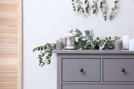 Stylish chest of drawers decorated with beautiful eucalyptus garland and candles indoorsの写真素材