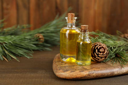 Pine essential oil, cone and branches on wooden table. Space for textの写真素材