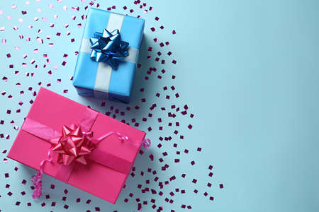 Gift boxes and shiny confetti on light blue background, flat lay. Space for textの写真素材