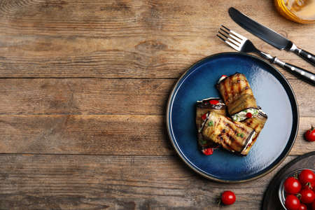Delicious baked eggplant rolls served on wooden table, flat lay. Space for textの写真素材