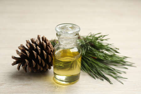 Pine essential oil, cone and branches on light wooden table, closeupの写真素材