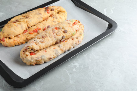 Baking tray with raw homemade Stollens on gray marble table, space for text. Traditional German...