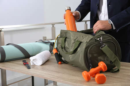 Businessman packing sports stuff for training into bag in office, closeupの写真素材