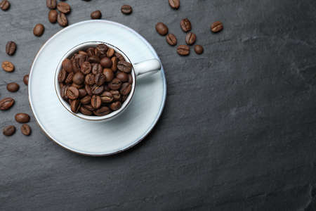 Cup with roasted coffee beans on black table, flat lay. Space for textの写真素材