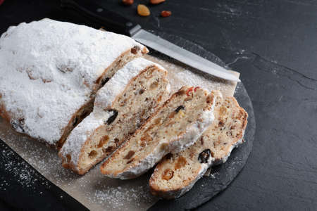 Traditional Christmas Stollen with icing sugar on black tableの写真素材